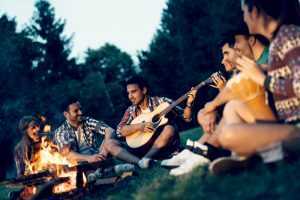 friends playing guitar around a campire