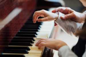 zoomed in teacher and student hands on a piano